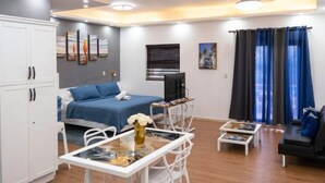 Quarto de hotel moderno com cama, escrivaninha, cadeira, televisão e janela com cortinas.