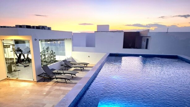 Un espace piscine aménagé sur le toit, avec des chaises longues et du matériel d’exercice.