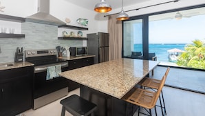Een moderne keuken met granieten aanrechtbladen, roestvrijstalen apparatuur en een groot eiland met barstoelen.