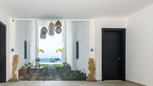 En modern hall med utsikt över havet, med en skulptur i trä föreställande ett sjöhäst, en mönstrad matta och en mörk dörr.