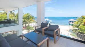 Una stanza moderna con un'ampia finestra vista spiaggia e mare. Sono presenti due divani grigi e un tavolino.