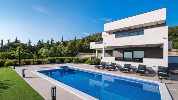 Un edificio moderno de dos pisos con piscina y sillas de descanso.
