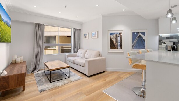 A modern living room with a sofa, coffee table, and dining area with chairs. - Bright & Spacious 1-bed in Vibrant Sydney (Sydney)