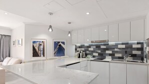 A modern kitchen with white cabinetry, a marble island, and a tiled backsplash. - Bright & Spacious 1-bed in Vibrant Sydney (Sydney)