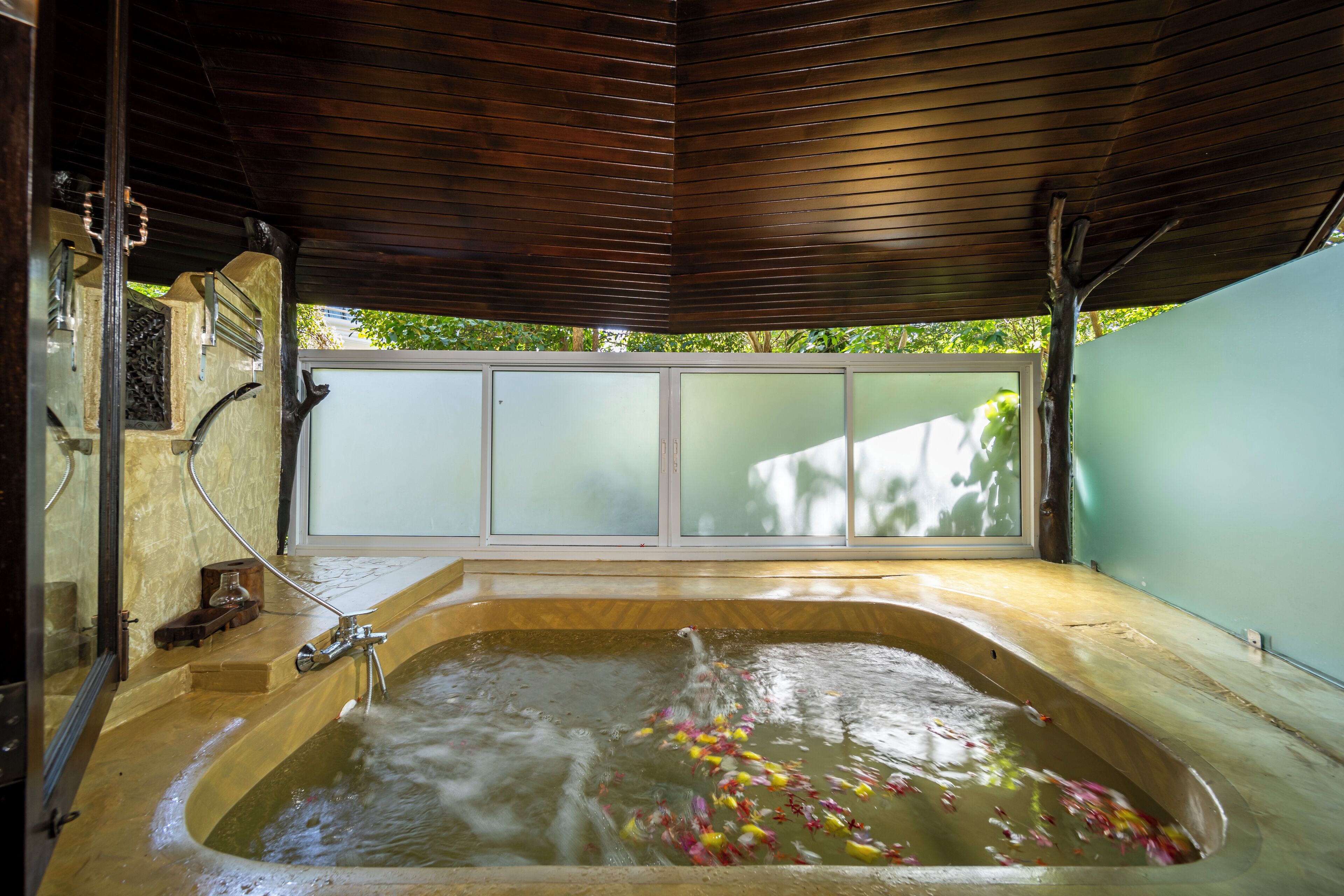 Un jacuzzi con techo de madera y vistas al verdor exterior.