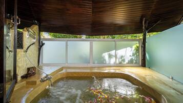 Un jacuzzi con techo de madera y vistas al verdor exterior.
