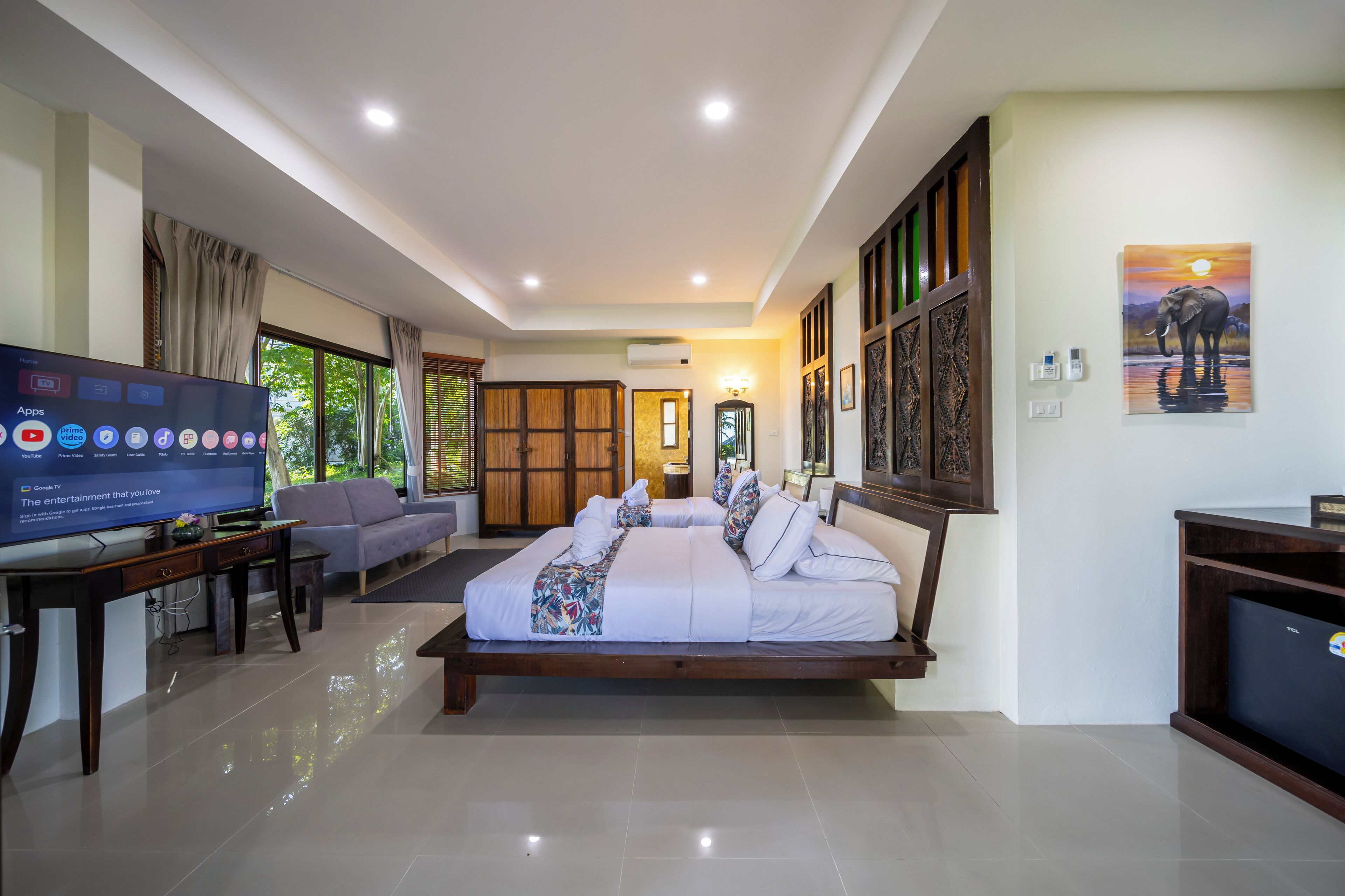 A modern hotel room with a large bed, a TV, a sofa, and a desk.