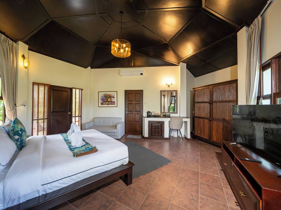 A hotel room with a large bed, a desk, a television, and a wardrobe.