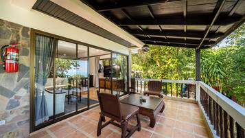 Un patio techado al aire libre con una mesa de comedor y sillas, un extintor y vistas al exterior.