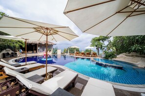 Una piscina al aire libre, sombrillas, sillones reclinables de piscina