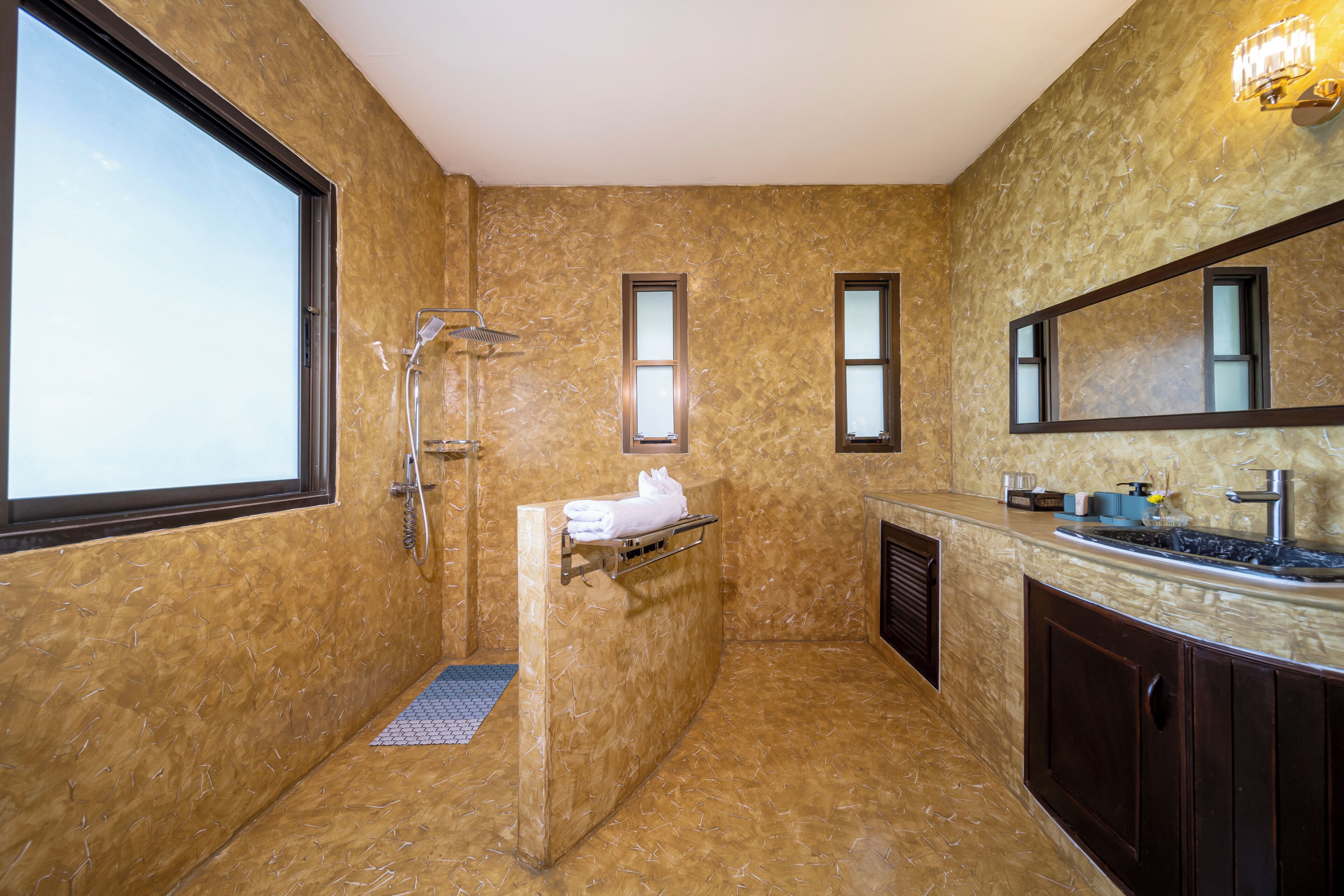 A bathroom with a large window, a shower, a sink, and a mirror.