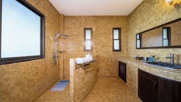 A bathroom with a large window, a shower, a sink, and a mirror.