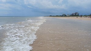 Une plage avec des vagues, un rivage sablonneux et des bâtiments en arrière-plan.