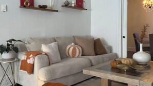 A living room with a sofa, a coffee table, a chandelier, and decorative items on shelves. - Bright & Spacious Home close to NYC and World Cup (Bayonne)