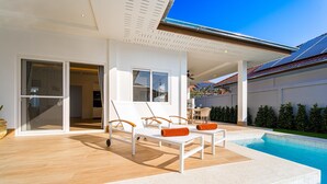 Ein modernes Haus mit Swimmingpool, Außenmöbeln und einer überdachten Terrasse.
