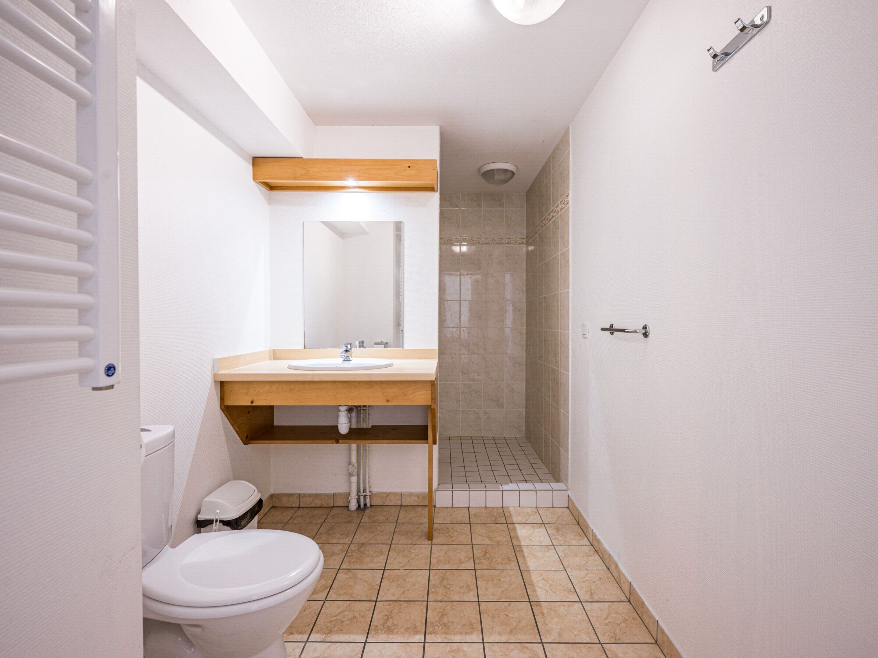 Een badkamer met toilet, wastafel, spiegel, douche en een handdoekhouder.