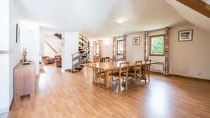 A spacious room with a wooden floor, a dining table with chairs, a staircase, and a view of greenery outside. - Birdie F Ndeg21 - 5p10 (Giez)