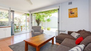 A modern living room with a sofa, a coffee table, and a chair. There is a sliding glass door leading to an outdoor patio area. - Sunset Views walking distance to Fremantle (Fremantle)