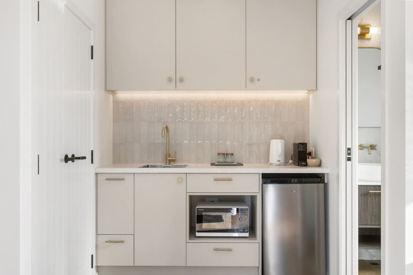 A modern kitchen with white cabinetry, a stainless steel dishwasher, and a built-in oven.