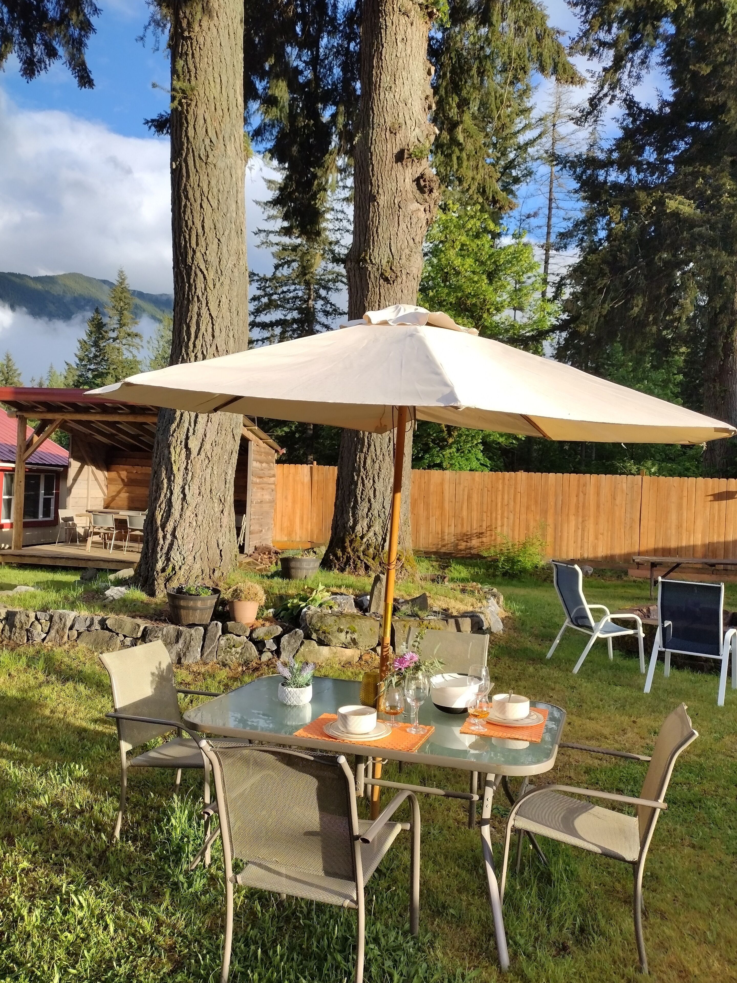 An outdoor dining area with a table, chairs, and an umbrella.