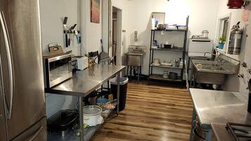 A kitchen with stainless steel appliances, wooden flooring, and a sink area.