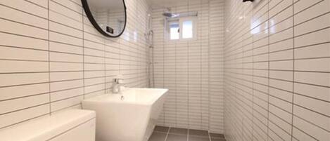 A narrow bathroom with white tiled walls and floor, a white sink, and a mirror.