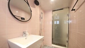 A bathroom with a white sink, a mirror, and a glass shower enclosure. - Business Hotel J7 Busan (Busan)