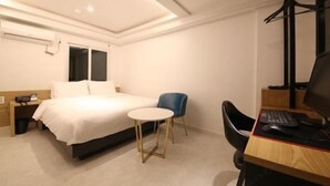 A hotel room with a bed, a desk with a computer, a chair, and a small table. - Business Hotel J7 Busan (Busan)