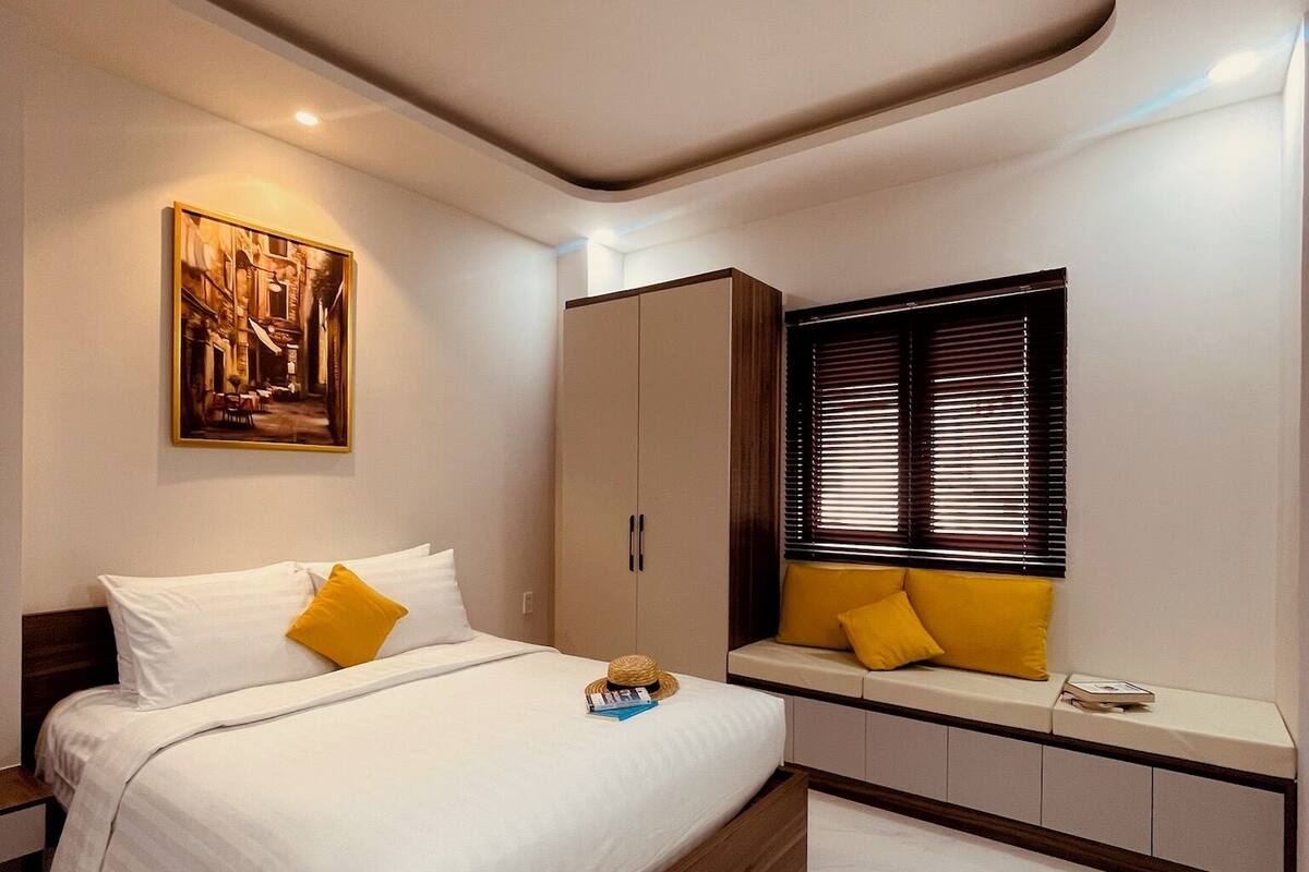 Un dormitorio moderno con una cama grande, un armario, una zona de estar con cojines y una lámpara de techo.