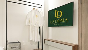 Une chambre d’hôtel équipée d’un lit, d’un porte-peignoir, d’une télévision et d’une étagère en bois.