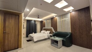A modern hotel room with a bed, a glass table, a green armchair, and wooden paneling on the walls. - HOTEL SEA SOUL AYAN GROUP OF HOTEL  (Digha)