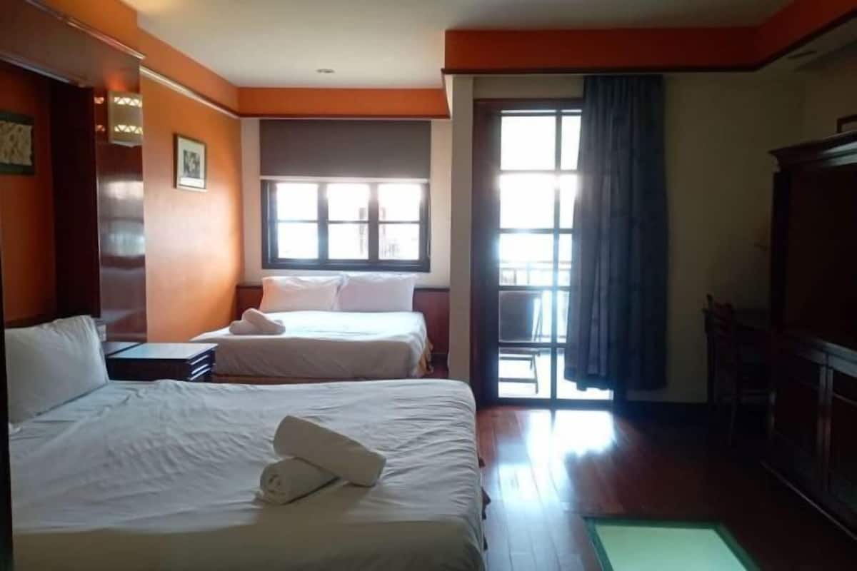 A hotel room with two beds, a large window, and a view of the outside.
