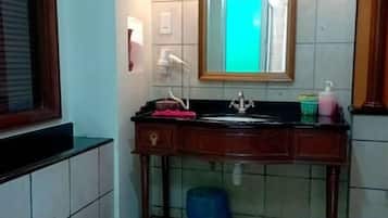 Une salle de bain avec un lavabo, un miroir et une fenêtre.