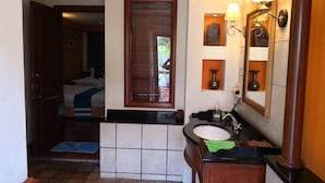 A bathroom with a sink, mirror, and two wall-mounted lamps. - Premium Water Chalet 2 (Port Dickson)