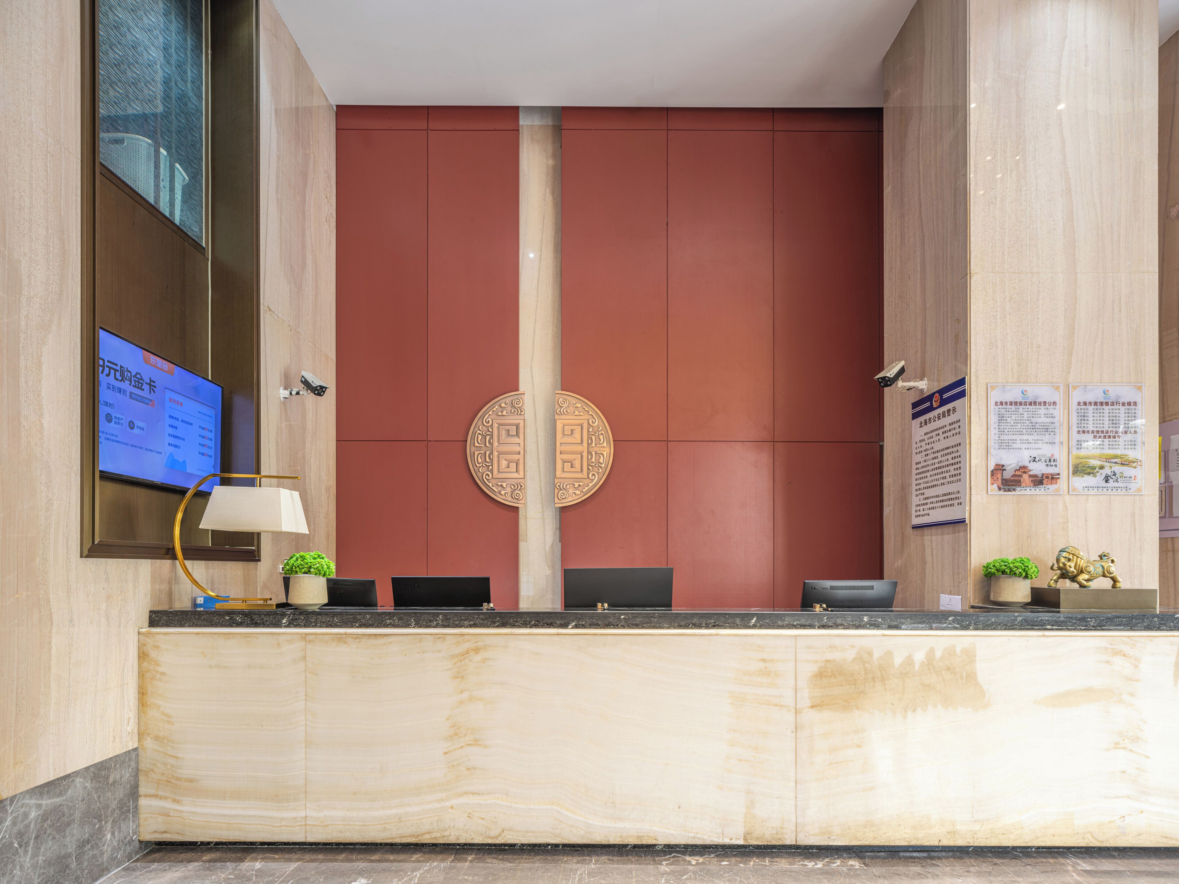 A reception desk with a digital screen, a lamp, and a decorative emblem.