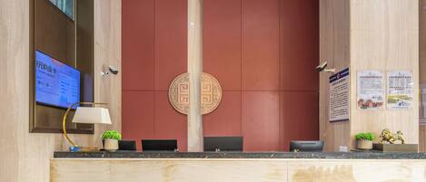 A reception desk with a digital screen, a lamp, and a decorative emblem.
