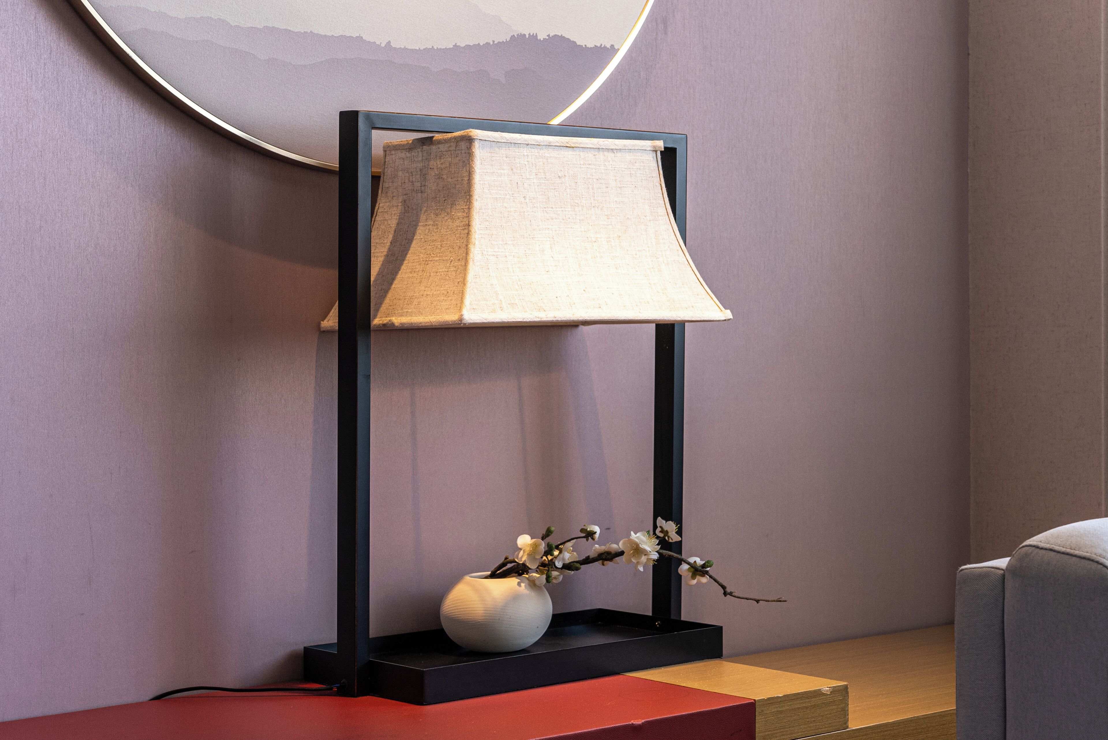 A modern floor lamp with a vase of flowers on a wooden platform.