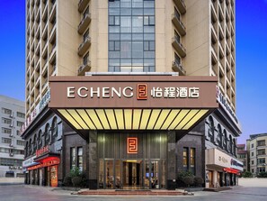 Un hôtel à l’architecture moderne, avec une façade remarquable, une entrée imposante dotée de portes vitrées et d’une enseigne au néon.