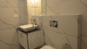 A modern bathroom with a white sink, toilet, and marble-patterned walls. - HOTEL CRESTA INN (Agra)
