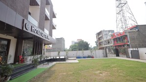 A hotel with a modern facade, outdoor seating area, and a grassy courtyard. - HOTEL CRESTA INN (Agra)