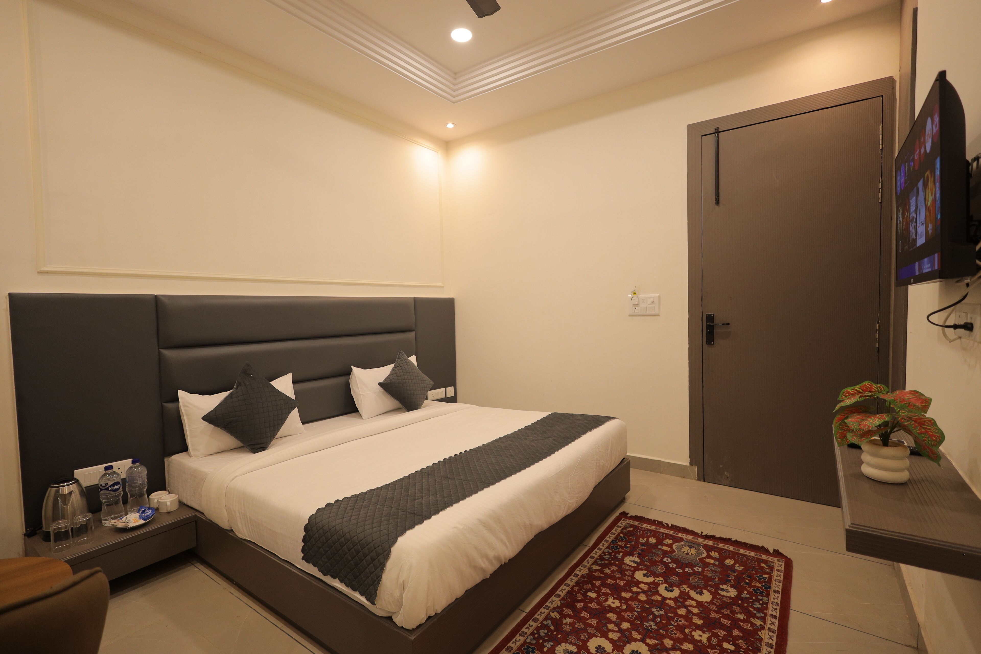 A bedroom with a large bed, bedside tables, a nightstand, a TV, and a door.
