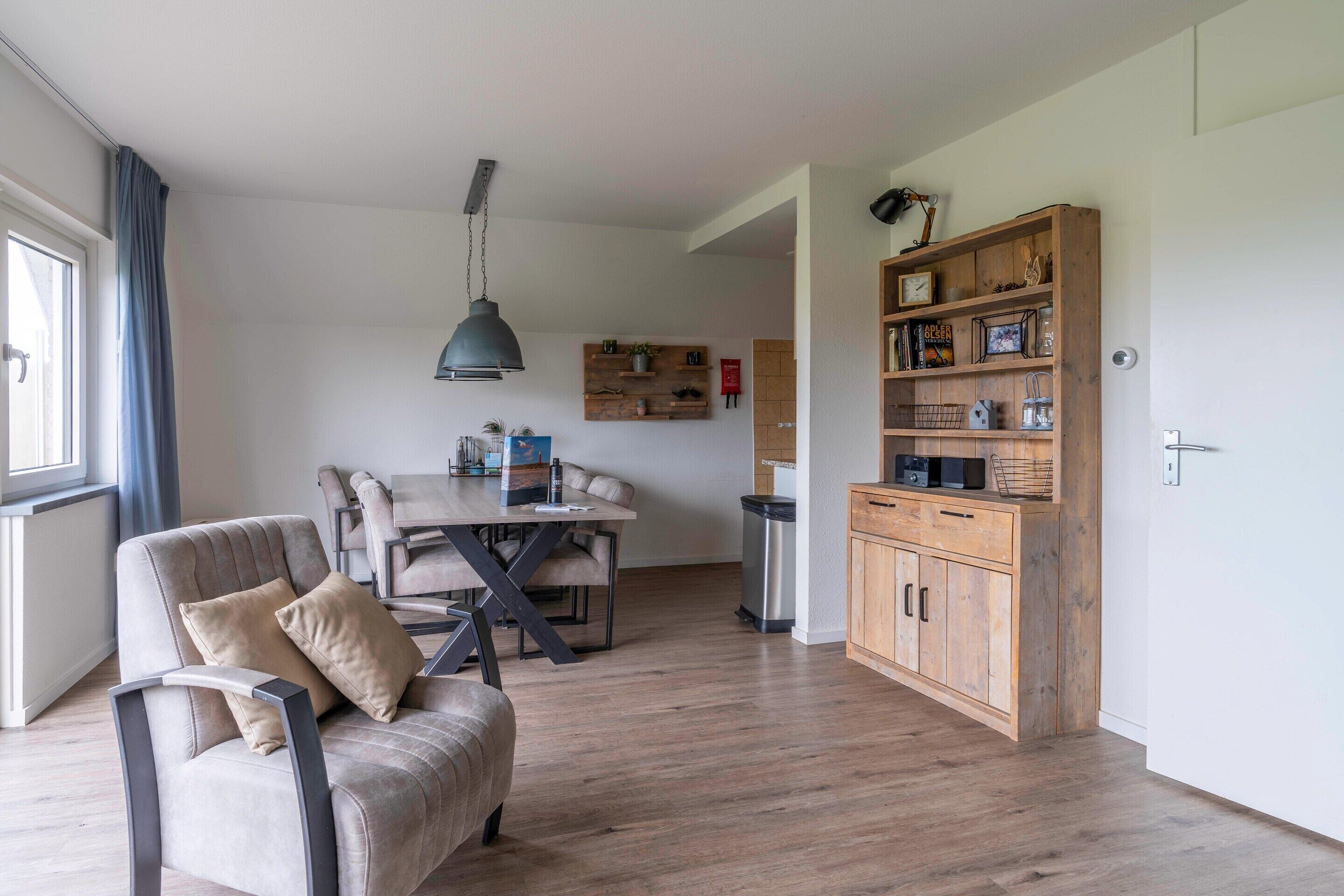 A modern living room with a sofa, dining table, and a wooden cabinet.