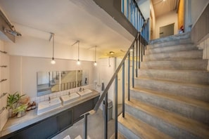 A staircase with a modern design, leading to a bathroom with two sinks and a large mirror. - Ralph Bangkok (Bangkok)