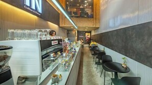 A coffee shop interior with a counter, seating area, and a visible espresso machine. - Ralph Bangkok (Bangkok)