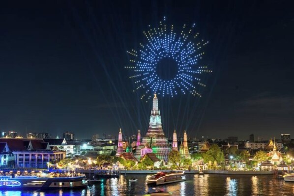 A nighttime cityscape with a prominent illuminated tower and fireworks display.