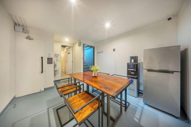 A modern kitchen with a wooden dining table, metal chairs, a stainless steel refrigerator, and a built-in oven.