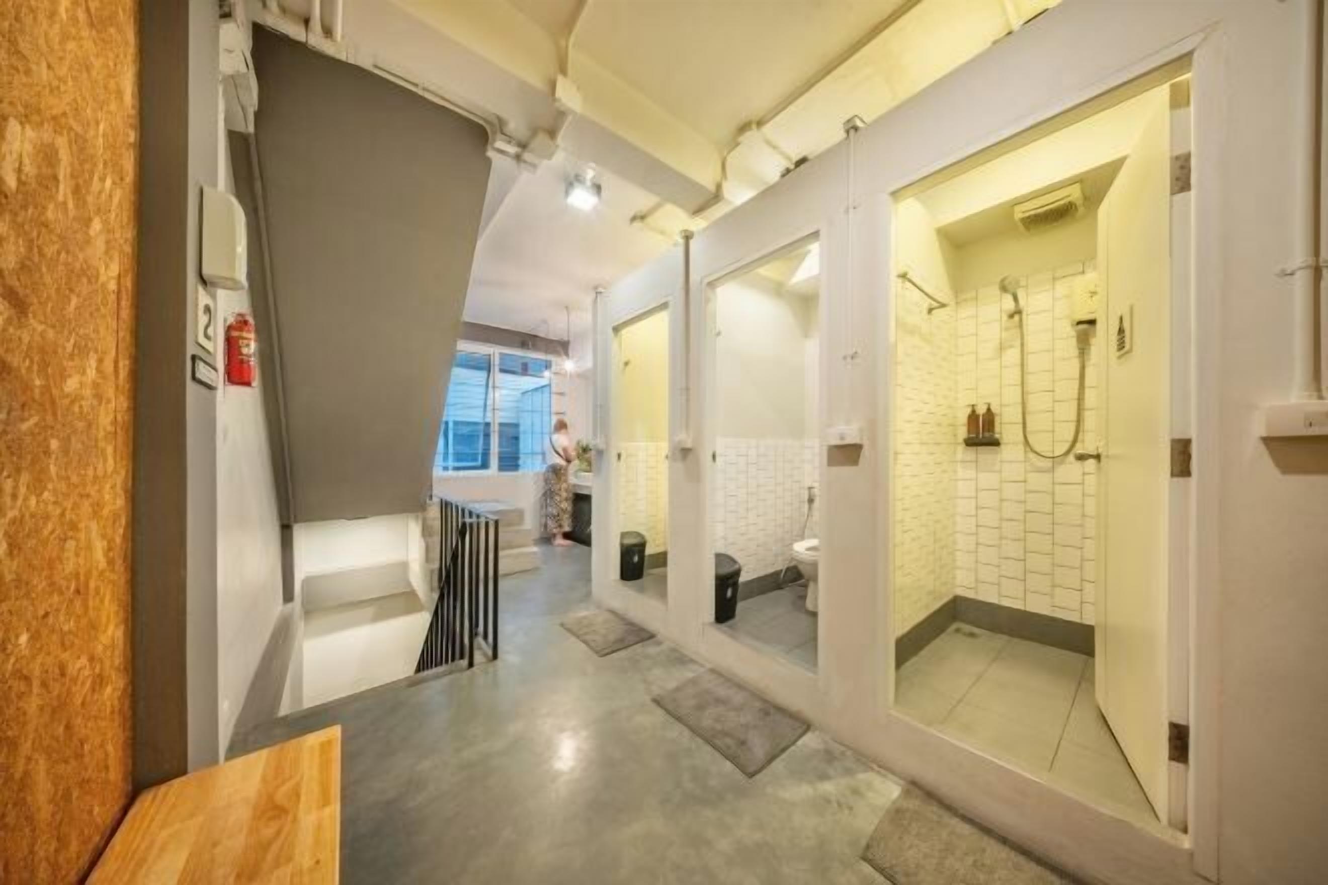 A modern bathroom with a shower, a toilet, and a sink. There is a window in the background.