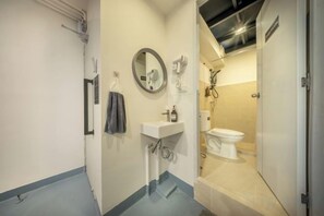 Un baño con un lavamanos blanco, espejo y toallero.