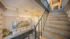 A modern bathroom with dual sinks, a large mirror, and a staircase with metal railings. - Ralph Bangkok (Bangkok)