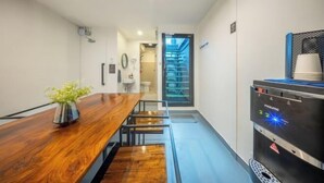 A modern hotel room with a wooden dining table, a water dispenser, and a view of the city through the window. - Ralph Bangkok (Bangkok)